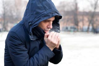 Man breathing on his hands to keep them warm