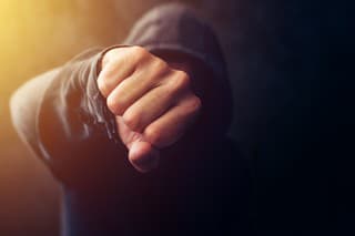 Crime, violence and bullying concept with hooded criminal person, selective focus on fist