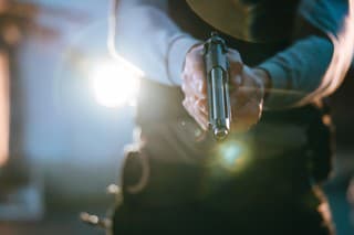 Task force officer holding a handgun in the middle of the crime scene at night.