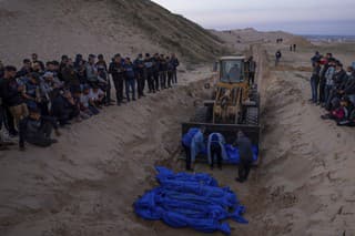 Buldozér vykladá telá Palestínčanov zabitých v bojoch s Izraelom a odovzdaných izraelskou armádou počas hromadného pohrebu v Rafahu v Pásme Gazy.