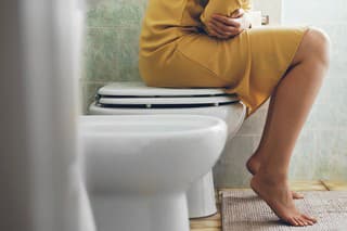 Unrecognizable woman on the toilet with stomach pain.