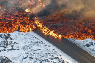 Pohľad na lávu tečúcu na potrubie s horúcou vodou, ktorá tečie po ceste vedúcej k Modrej lagúne na polostrove Reykjanes na Islande vo štvrtok 8. februára 2024.