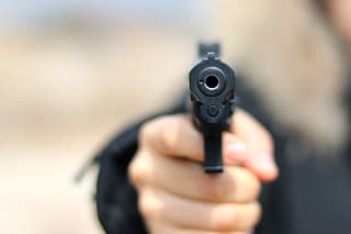 Woman pointing a gun at the target on soft background.