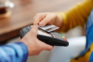 Close-up of unrecognizable customer choosing contactless payment using credit card while waitress accepting payment over nfc technology
