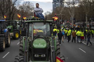 Farmár sedí na streche traktora počas protestu poľnohopodárov pred budovou zastupiteľského úradu Európskej komisie (RK) v Madride v pondelok 26. februára 2024.