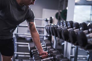 Young man taking dumbbells from a rack