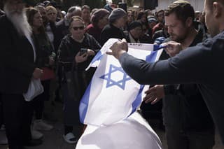 Príbuzní Yitzhaka Zeigera dávajú izraelskú zástavu na jeho telo počas jeho pohrebu na cintoríne v Jeruzaleme.