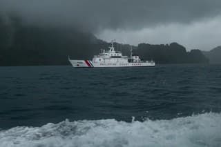 From the window of a passing ferry, a Philippine Coast Guard vessel is seen at sea during rainy season off the coast of El Nido, Palawan, Philippines.