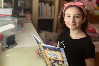 Rebecca (8) rada vo svojej knižnici siahne po knihe.