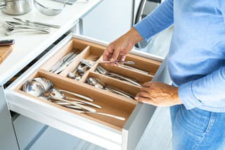 Unrecognizable woman organizing kitchen drawer with silverware. High resolution 42Mp studio digital capture taken with SONY A7rII and Zeiss Batis 40mm F2.0 CF lens