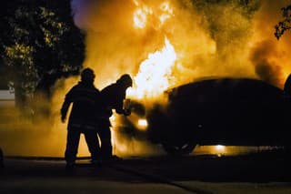 Firemen fighting a flaming car during night time