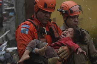 Príslušníci záchranných zložiek odnášajú 4-ročné dievčatko, ktoré vytiahli zo zrúteného domu počas silného dažďa v meste Petrópolis v štáte Rio de Janeiro na juhu Brazílie.