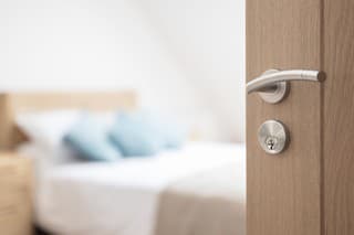 Hotel room or apartment doorway with key and keyring key fob in open door and bedroom in background