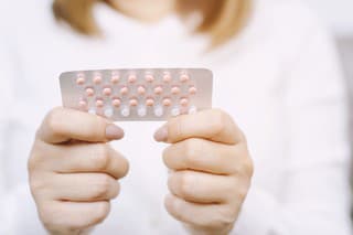 Woman hands opening birth control pills in hand. eating Contraceptive pill. Contraception reduces childbirth and pregnancy concept.