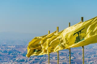 Jarjouaa, Lebanon - September 26, 2015: Hezbollah flags fly over southern Lebanese land liberated from occupying Israeli forces by Hezbollah in 2000. The Arabic text above the Hezbollah logo reads 