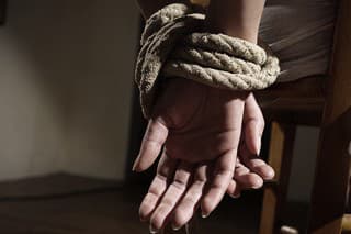 Young woman tied to a chair in a empty room, hands close up