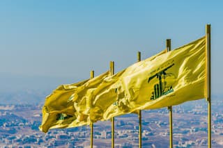 Jarjouaa, Lebanon - September 26, 2015: Hezbollah flags fly over southern Lebanese land liberated from occupying Israeli forces by Hezbollah in 2000. The Arabic text above the Hezbollah logo reads 