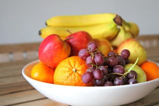 a bowl of fresh fruit set on a wooden table