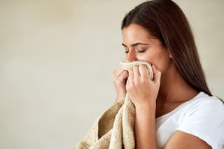 Shot of young woman enjoying the smell of freshly washed towels