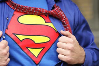 Penfield, New York, USA - October 30, 2009: Young man dressed in a Superman costume pulls off his outer shirt and tie.