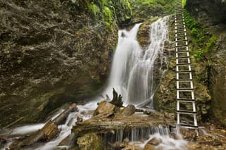 A technically aided trail along a waterfall in a lush gorge in Slovensky Raj in Slovakia.