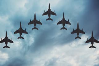 Fighter jets arranged in a V shaped flying formation under dramatic overcast skies.  Composite image.