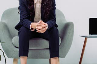 thoughtful young businesswoman sitting in armchair and looking away