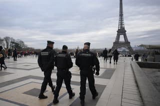 Policajti  hliadkujú neďaleko Eiffelovej veže v Paríži.