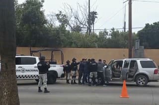 Na videosnímke policajti prehľadávajú mužov na kontrolnom stanovištii v meste Ensenada.