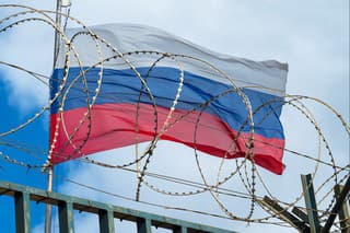 View of russian flag behind barbed wire against cloudy sky. Concept.