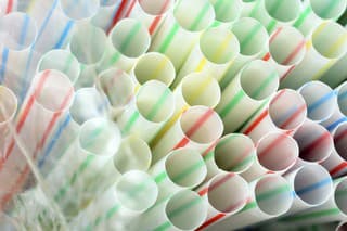 Colored plastic straws under plastic bag close up for plastic background