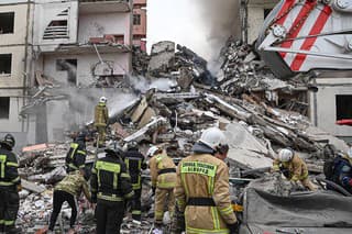 Príslušníci ruských záchranných zložiek zasahujú pred čiastočne zrútenou bytovkou po nedeľňajšom útoku v ruskom meste Belgorod 12. mája 2024.