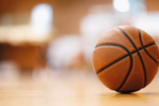 Close-up image of basketball ball over floor in the gym. Orange basketball ball on wooden parquet.