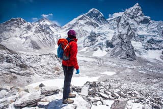 Woman standing on top of Kala Patthar summit on Himalayan range and looking at beautiful view with mt. Everest and lhotse