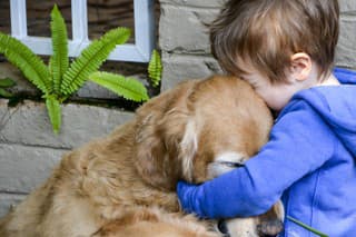 Little boy hugging and showing affection and love for his best friend, a cuddly golden retriever.