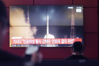 Ľudia sledujú archívnu snímku balistickej rakety, ktorú vystrelili Severná Kórea na železničnej stanici v Soule.