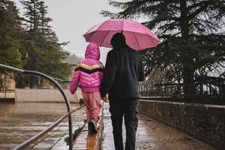 Father with daughter exploring city under the rain.