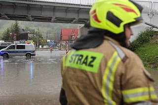 Poľskí hasiči zasahujú po zaplavení cesty pod železničným viaduktom v dôsledku silných búrok.