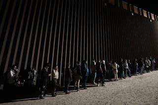 Ľudia stoja v rade pri hraničnom múre a čakajú na žiadosť o azyl po prekročení hranice z Mexika.