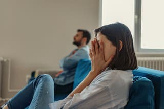 Unhappy Couple After an Argument in the Living Room at Home. Sad Pensive Young Girl Thinking of Relationships Problems Sitting on Sofa With Offended Boyfriend, Conflicts in Marriage, Upset Couple After Fight Dispute, Making Decision of Breaking Up Get Divorced