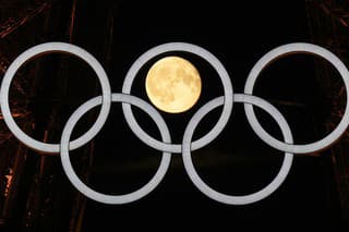 Na snímke spln mesiaca za olympijskými kruhmi, ktoré visia na Eiffelovej veži.