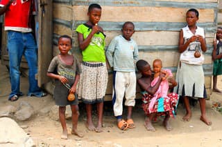 Village, Uganda - March 6, 2012: Ugandan children standing at the wall of the house in the village.