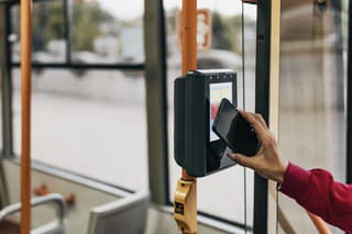 Woman buying tickets in the bus while traveling. Beautiful woman is paying transport ticket with mobile phone.