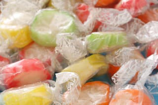 Candy wrapped with transparent plastic getting out from paper bag. Shallow depth of field, focus on image bottom