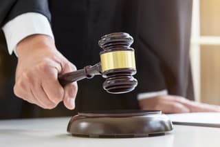 Close up of Male lawyer or judge hand's striking the gavel on sounding block, working with Law books, report the case on table in modern office, Law and justice concept.