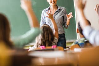 Happy female teacher asked a question during a class at elementary school.