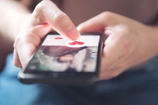 Finger of woman pushing heart icon on screen in mobile smartphone application. Online dating app, valentine's day concept.