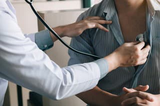 Asian doctor is using a stethoscope listen to the heartbeat of the elderly patient.