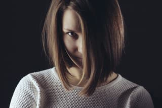 Woman hair covered face portrait in studio on dark background