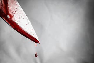 close-up of man holding knife smeared with blood and still dripping.